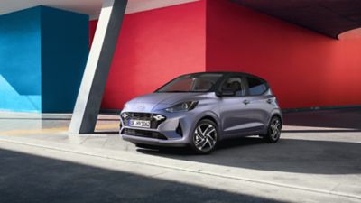 De Hyundai i10 geparkeerd voor een rode en blauwe muur.