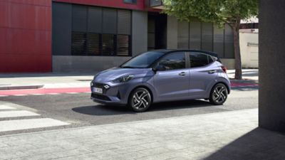 De Hyundai i10 van voren gezien, geparkeerd voor een modern gebouw