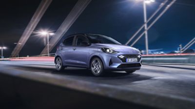 The new Hyundai i10 driving over a modern bridge at night.