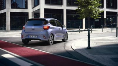 The Hyundai i10 in purple turning right on a city street.