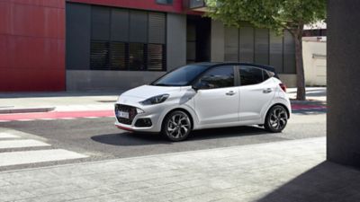 Ein weißer Hyundai i10, schräg von vorne gesehen, hält vor einem Zebrastreifen. 