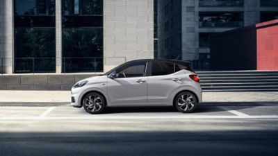 Zijaanzicht Hyundai i10 geparkeerd voor een gebouw.