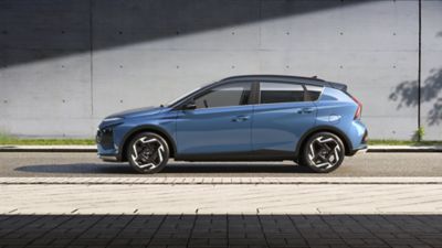 Zijaanzicht van een blauwe Hyundai BAYON geparkeerd in een stedelijke straat.