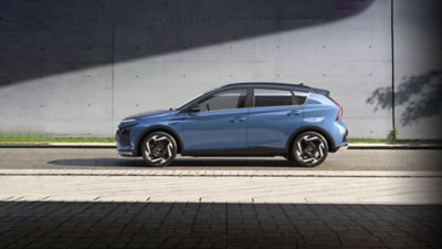 Side view of the blue Hyundai BAYON driving on a street. 