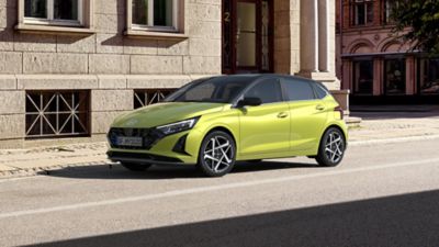 La Hyundai i20 est garée devant le bâtiment marron.