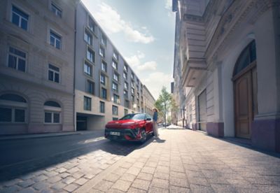 The all-new KONA N Line in red parked next to a modern building.