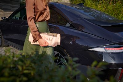 Woman walking past IONIQ 6 whilst parked.