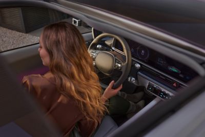 woman with brown t-shirt and green skirt in the driver’s seat of the Hyundai IONIQ 6 
