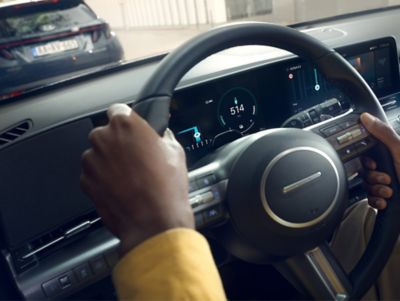 A man holding the steering wheel of the Hyundai KONA Electric SUV.