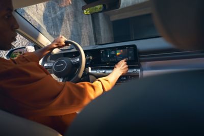 A man using the touchscreen with surround view monitor of the Hyundai KONA Electric to park.