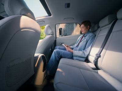 A woman sitting in the rear seat of the Hyundai KONA Electric.
