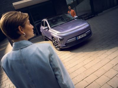 A man standing next to the Hyundai KONA Electric in blue.