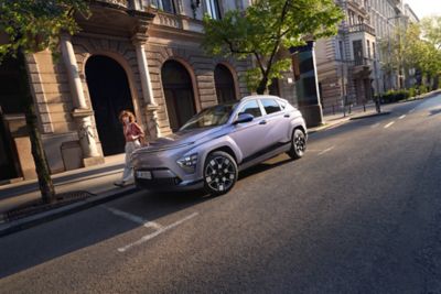 The Hyundai KONA Electric in blue parked in front of building. 