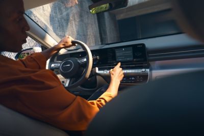A man driving the all-new Hyundai KONA while using its touchscreen panel.