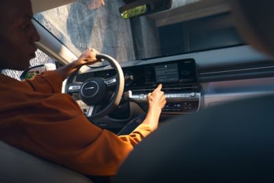 Man gebruikt centrale touchscreen in Hyundai KONA Electric. 