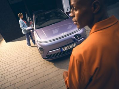 Hyundai KONA Eléctrico visto de frente junto a un hombre y una mujer.