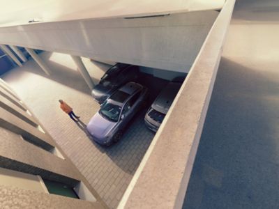 Person watching a car park itself between two other cars using Remote Smart Parking Assist (RSPA).