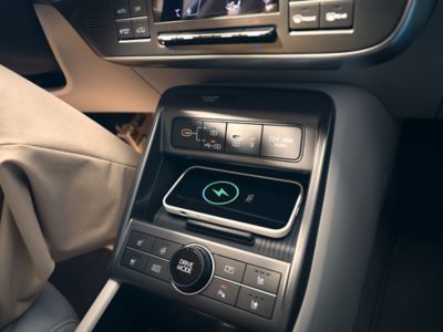 A smartphone in the wireless charger compartment inside the Hyundai KONA.