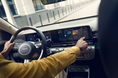 Un homme conduisant le tout nouveau Hyundai KONA tout en utilisant son écran tactile. 