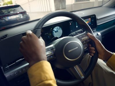 A close-up image of the steering wheel of the all-new Hyundai KONA while a man drives. 