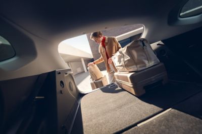 Une femme met des bagages dans le nouveau grand coffre de KONA Hybrid 2023