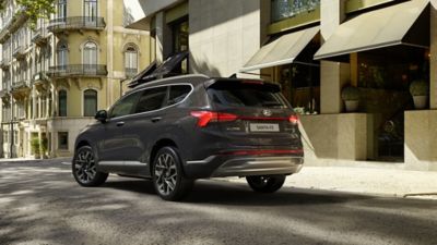 The Hyundai Santa Fe Plug-in Hybrid 7 seat SUV parked in front of a shop.