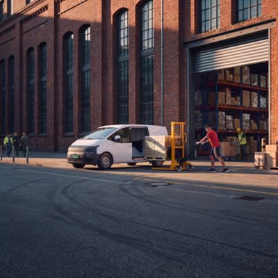 En mann laster inn i en STARIA Electric Varebil. Foto.