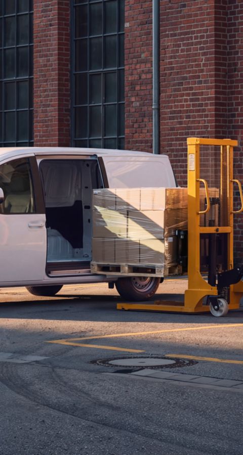 Hyundai STARIA Electric Varebil lastes med esker på paller utenfor et lager.