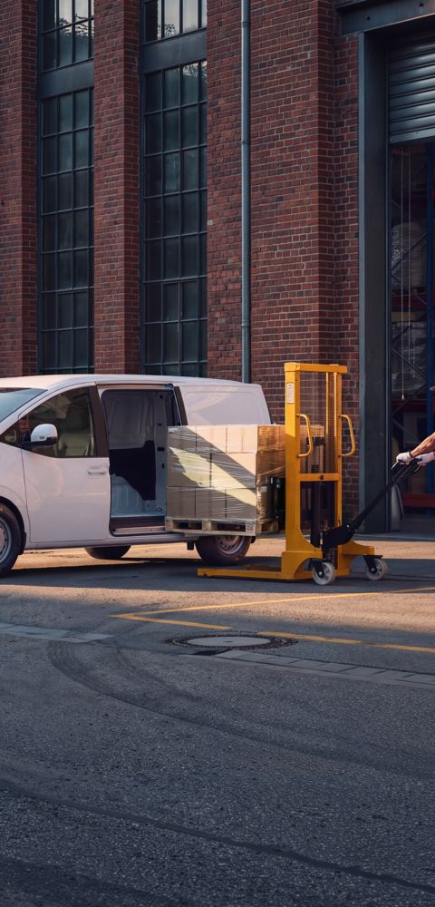 Hyundai STARIA Electric Varebil lastes med esker på paller utenfor et lager.
