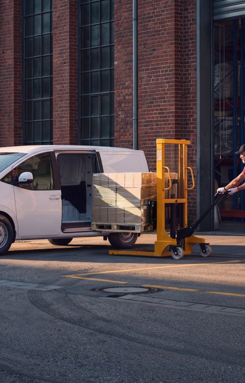 Elektriske Hyundai STARIA Cargo lastes med esker på paller utenfor et lager.