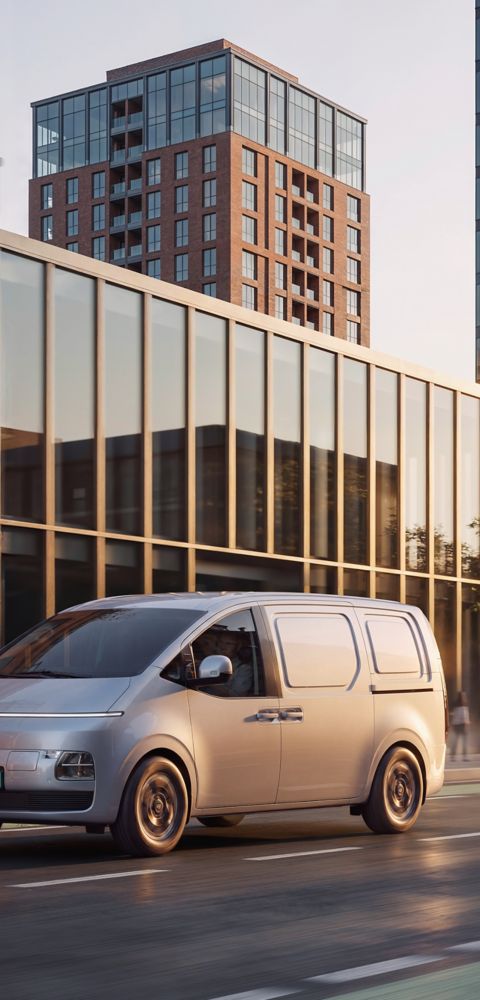 Hyundai STARIA sett forfra mens den kjører på en vei i byen.
