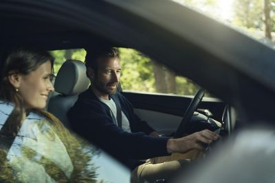 Looking inside a Hyundai through the passenger window, a couple inside looking at the touchscreen.