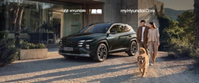 Hyundai Tucson parkerad utanför ett hus medan en familj promenerar med sin hund. Sommarkampanj för Hyundai Service och Hyundai Holiday Check.