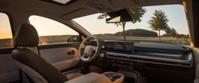 Interiör av Hyundai med vy genom vindrutan över landsväg och träd i solnedgång.