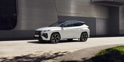 The Hyundai new TUCSON Hybrid driving on road passing modern building.