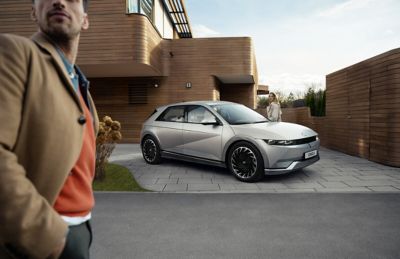 The all-electric Hyundai IONIQ 5 seen from the front parked by modern building.