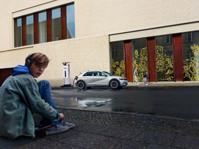 IONIQ 5 charging at station with boy in background.