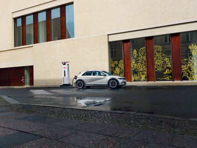 Hyundai IONIQ 5 next to a modern building charging