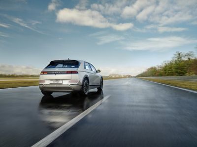 A Hyundai IONIQ 5 electric midsize CUV passing another car on a country road.