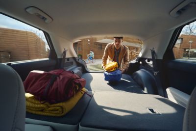 The IONIQ 5 boot space with folded seats, and a person adding two backpacks. 