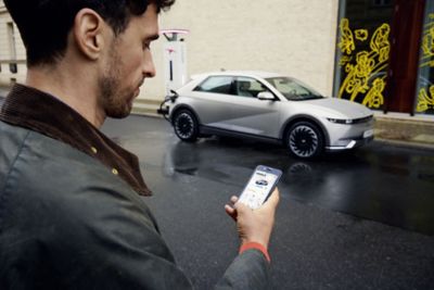 Man looking at the Bluelink app in front of his Hyundai IONIQ 5