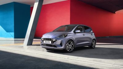 The Hyundai i10 parked in front of a red wall.