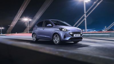 The Hyundai i10 driving on a city street at night time.