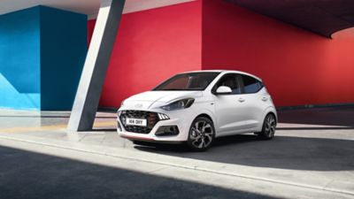 White Hyundai i10 in front of a red and blue building
