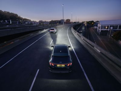 The Hyundai TUCSON Hybrid driving at night over a bridge. 