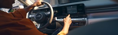 A woman behind the wheel of her Hyundai i30, using the touchscreen.