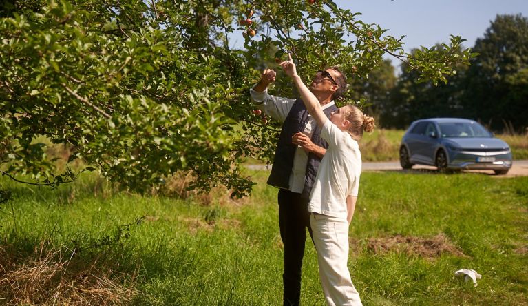 Unterwegs mit dem IONIQ 5 - Mann und Frau unter Apfelbäumen