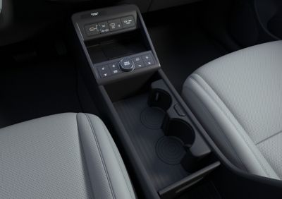 A woman putting her coffee on one of the rotational cup holders of the Hyundai KONA.