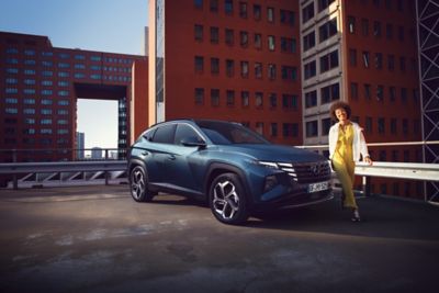 View of the Hyundai TUCSON SUV parked on a rooftop and a woman walking away from the car.