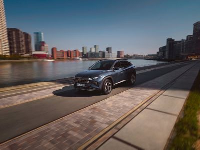 The Hyundai TUCSON driving through a city on a riverside. 